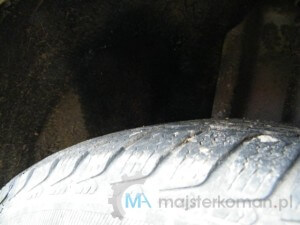 Zamalowane naprawione uszkodzenie Zamaskowana łatka w naprawianym nadkolu czarną farbą w sprayu