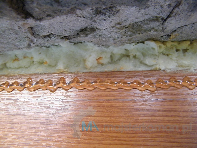 Nałożony uszczelniacz dekarski na futrynie okna